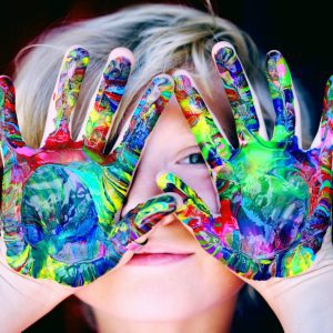 Vibrant close-up of a child's hands covered in colorful paint, expressing creativity and fun.