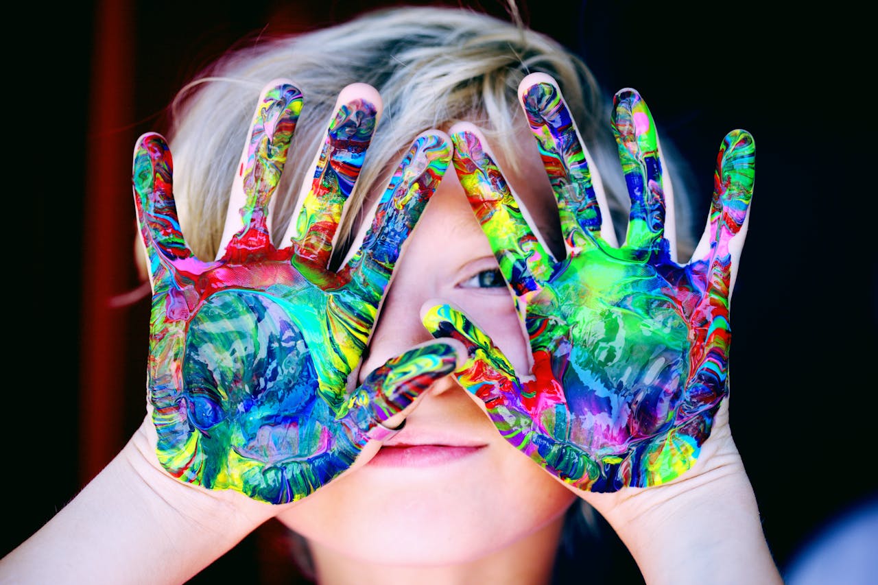 pexels-photo-1148998 Vibrant close-up of a child's hands covered in colorful paint, expressing creativity and fun.